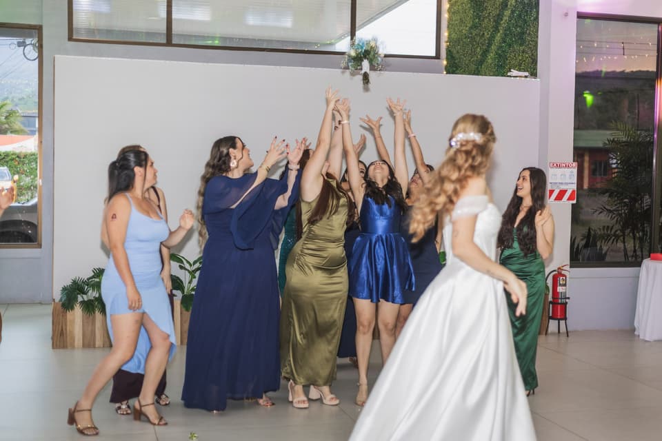 Invitadas con los brazos arriba esperando el ramo que lanza la novia