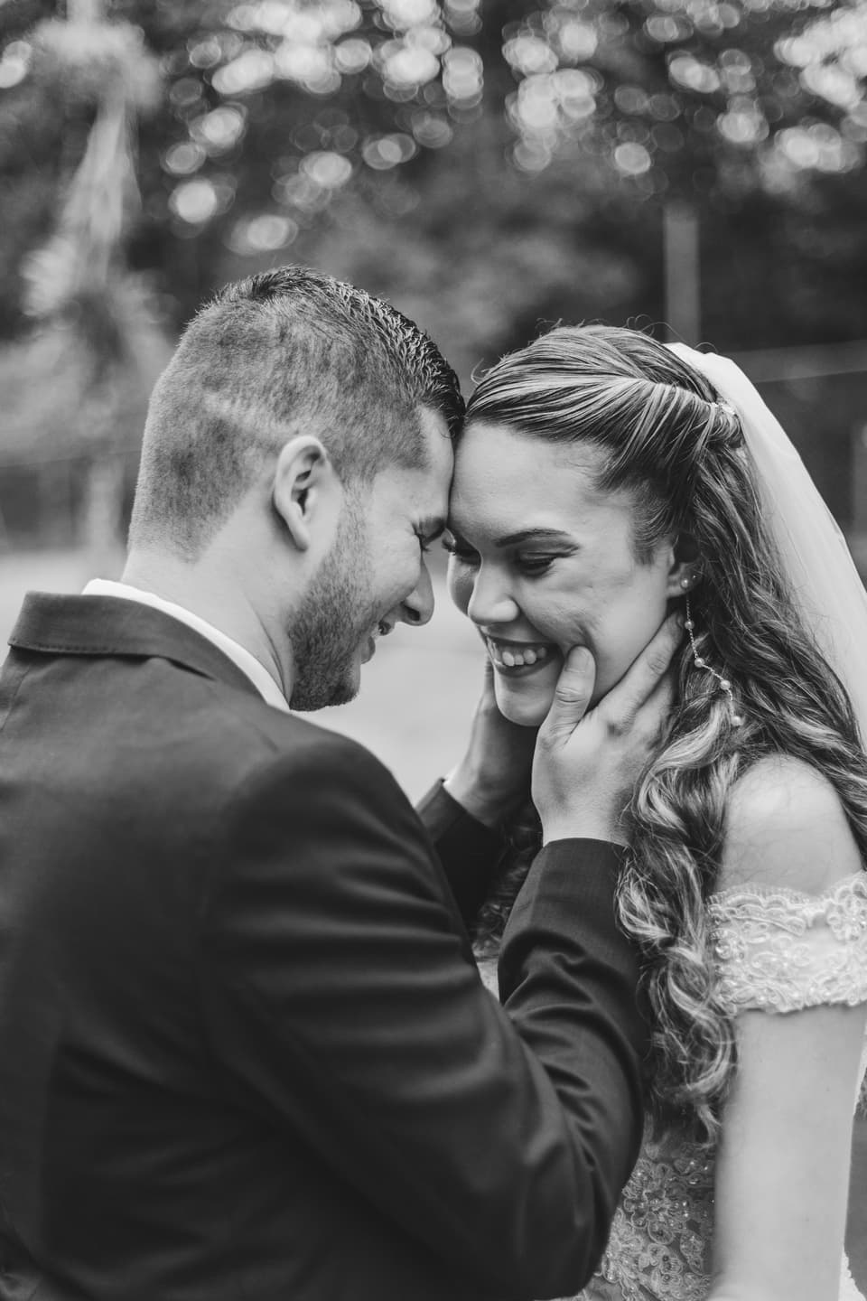 Novios con las frentes juntas, ella sonriendo, en blanco y negro