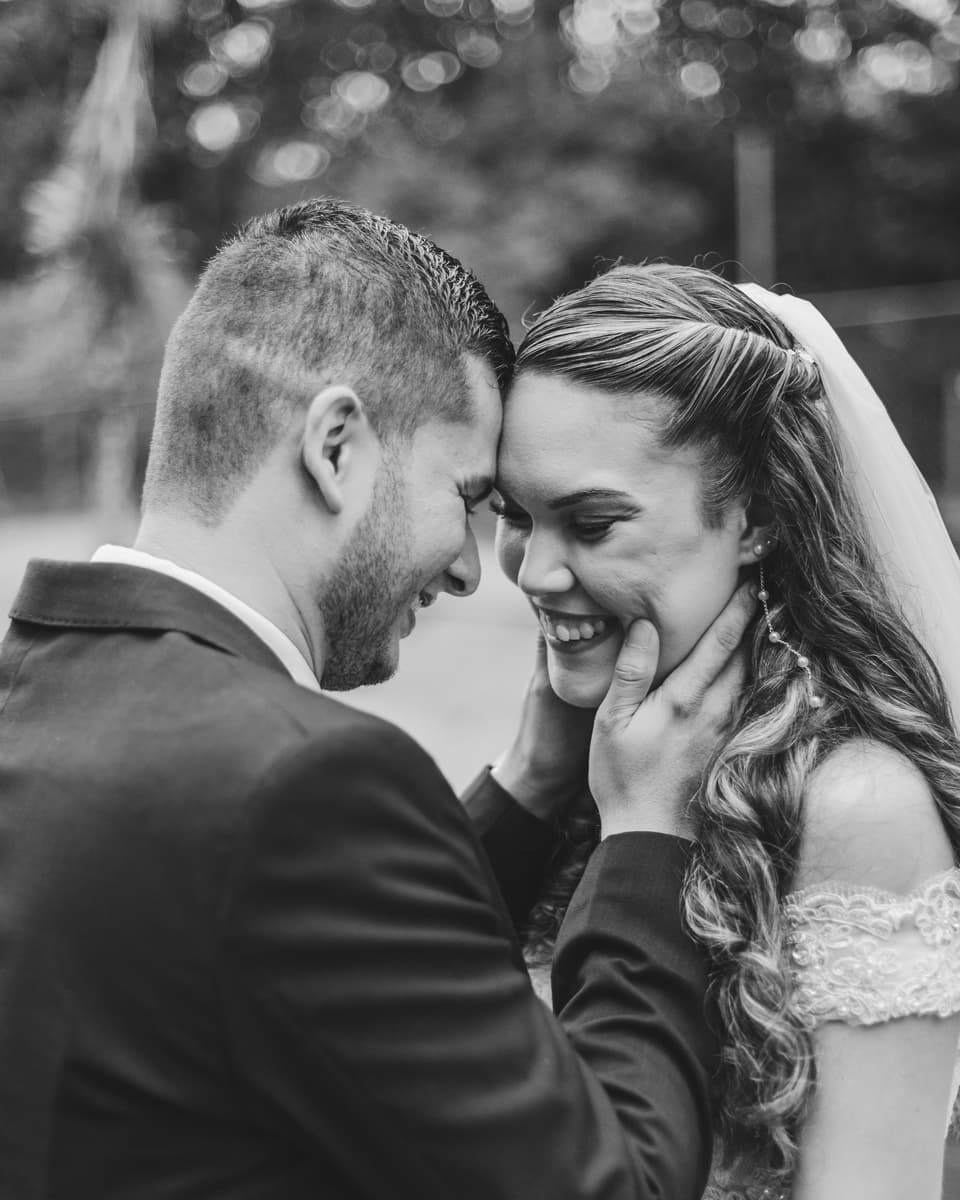 Novios con las frentes juntas, ella sonriendo, en blanco y negro