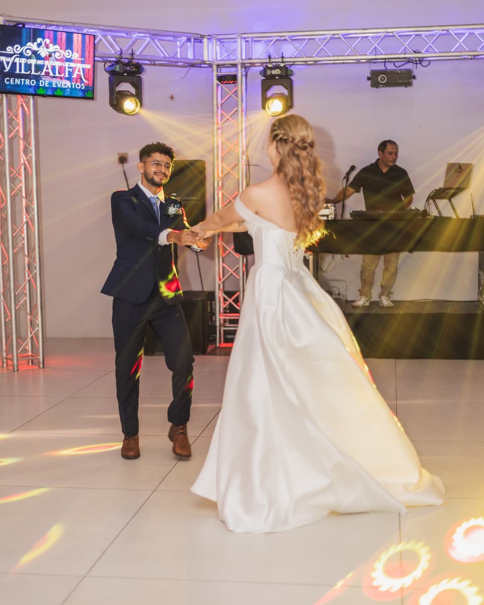 Novios en su primer baile sobre la pista, con luces de colores detrás
