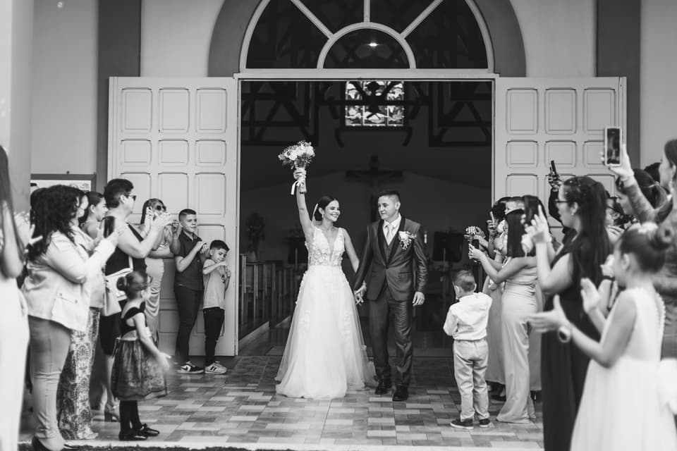 Novios saliendo de la iglesia entre los invitados que los aplauden, en blanco y negro