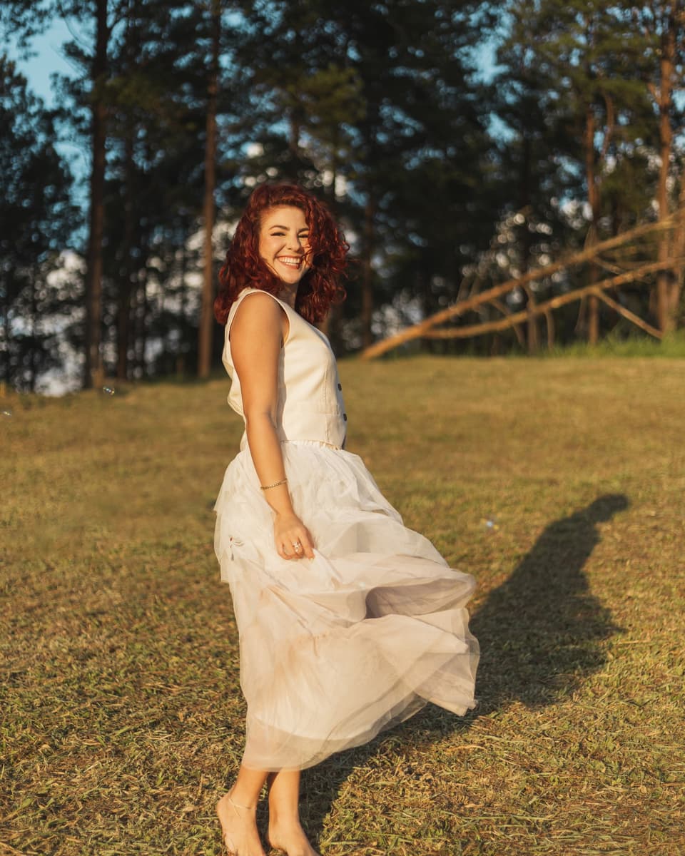 Fabiola Soto bailando descalza sobre el pasto, con el vestido en movimiento y una sonrisa